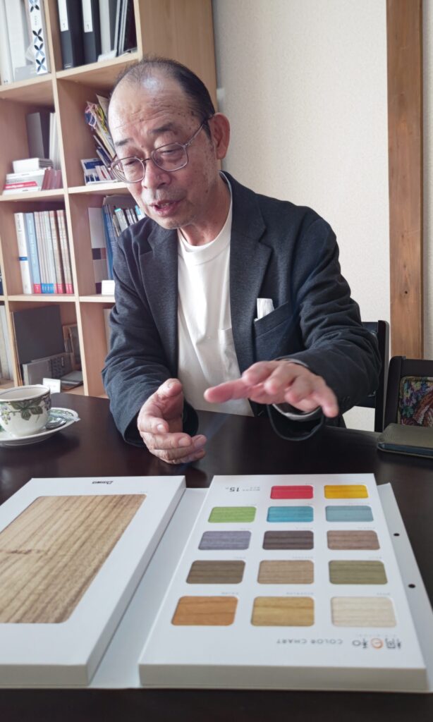桐材の色見本帳を前に、内装工事について語る塗装会社社長