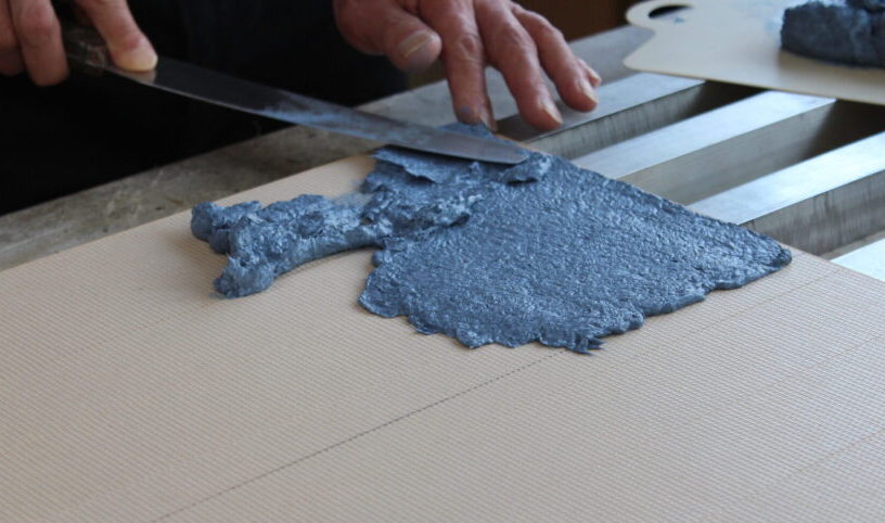 ブルーの塗料を板に広げていこうとする職人の手元