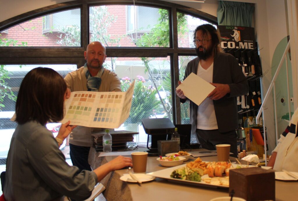 来場者に見本帳を手渡すルイージ社長と村上社長