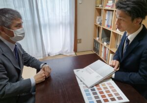 色見本帳を机に広げ、シラス壁の話に花を咲かせる高千穂シラス佐藤様とリアルカラー社長